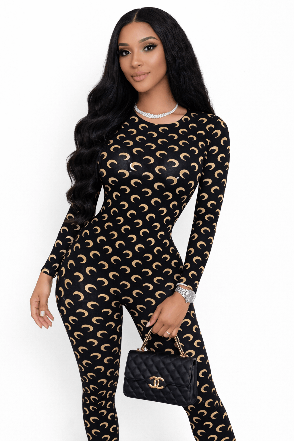 Woman wearing a black and gold patterned outfit with a matching handbag on a white background